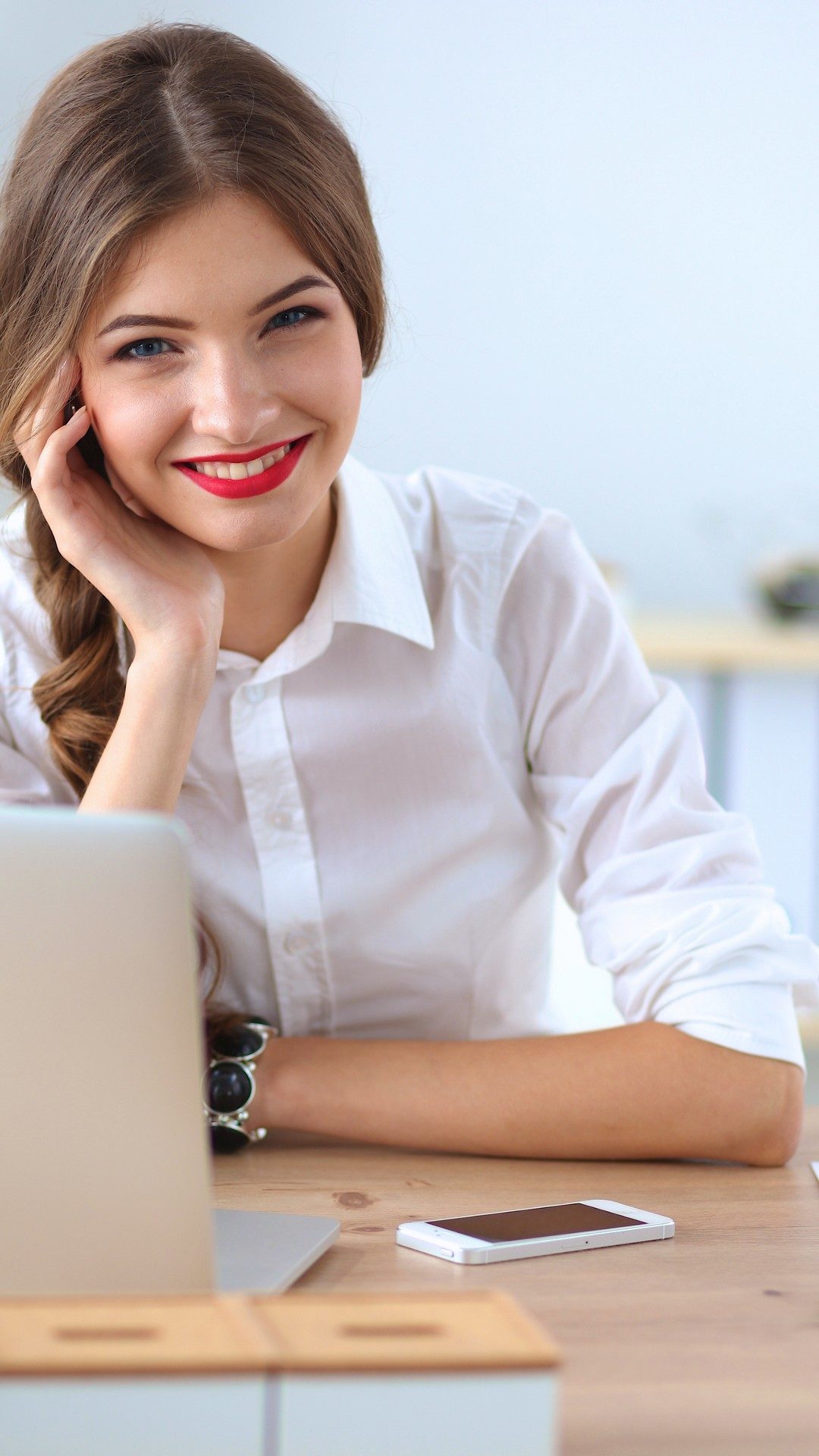 Attractive businesswoman sitting  on desk in the office